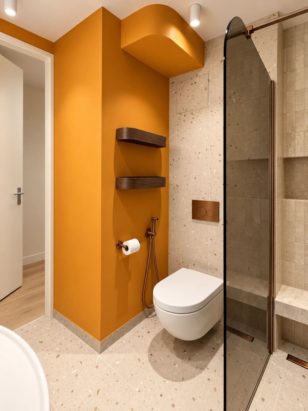 Hangtoilet met koperen bedieningsplaat, terrazzo tegels, een okergele wand en een inloopdouche met zitbank